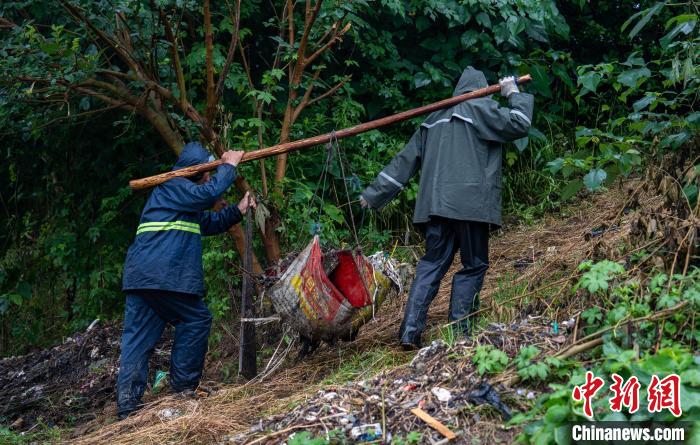 雨后水面垃圾增多,岸边变得潮湿。队员们穿着雨衣,踩着湿滑的泥土,艰难地搬运刚打捞上来的河道垃圾。 高博 摄