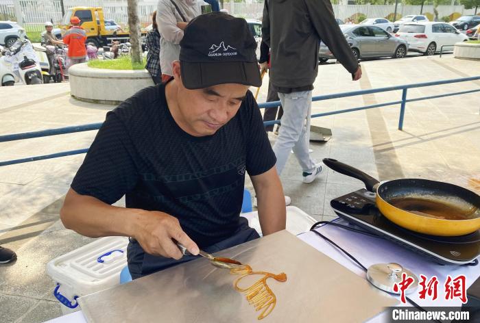 民间艺人现场演示糖画。 崔佳明 摄