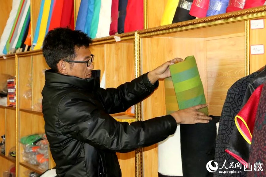 扎囊县残疾人就业创业基地负责人拉琼在整理店里的服饰。次仁龙布摄